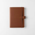 Brown leather notebook with a textured cover and elastic closure, placed on a white surface. A pen Royalty Free Stock Photo