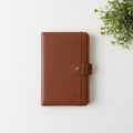 A brown leather-bound notebook with a snap closure lies on a white Royalty Free Stock Photo