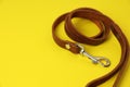 Brown leather dog leash on yellow background, closeup. Space for text Royalty Free Stock Photo