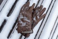 Brown leather gloves forgotten on a snow-covered bench in a winter park Royalty Free Stock Photo