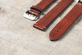 Brown leather handmade watch strap with steel buckle on rustic wooden surface. Copy space.