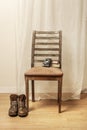 Brown leather hiking boots resting next to a emaciated wooden chair next to an old camera resting on the backrest Royalty Free Stock Photo