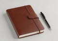 Brown leather journal with a black pen on a light background Royalty Free Stock Photo