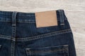 Brown leather label of blue jeans on back of jean with wood background. Royalty Free Stock Photo