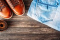 Brown leather men`s boots, belt and blue jeans on a dark wooden background, top view with copy space Royalty Free Stock Photo