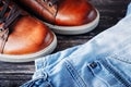 Brown leather men`s boots and blue jeans on a dark wooden background Royalty Free Stock Photo