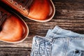 Brown leather men`s boots and blue jeans on a dark wooden background Royalty Free Stock Photo