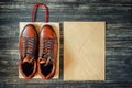 Brown leather men`s boots and kraft envelope on a wooden background, top view Royalty Free Stock Photo