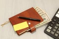 A brown leather notebook and black pen lie on an office desk. Cash dollars. Marker and note paper. Royalty Free Stock Photo