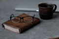 Brown leather notebook, pen, laptop and glasses on gray background Royalty Free Stock Photo