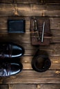 brown leather notebook  belt  boots with a metal ballpoint pen and eyeglasses on brown wooden background Royalty Free Stock Photo