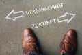 With brown leather shoes deciding between VERGANGENHEIT and ZUKUNFT (past and future in German)