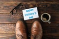 Brown leather shoes, inscription happy fathers day, cup of coffee and glasses on wooden background, space for text Royalty Free Stock Photo