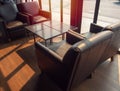 Brown leather sofa with wooden table on wooden floor near glass window in cafe Royalty Free Stock Photo