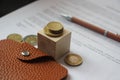 Brown leather wallet, coins and pen put on agreement. Business investment and real estate concept