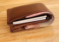 Brown leather wallet full of banknotes and credit cards. Men`s wallet on a wooden table. Money in a closed brown purse Royalty Free Stock Photo