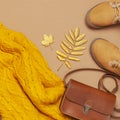 Brown leather women bag, orange knitted sweater, warm boots, golden autumn leaf on brown background top view flat lay. Fashionable Royalty Free Stock Photo