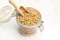 Brown lentils in a crystal jar with a wooden spoon on a kitchen counter