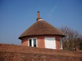 A brown local vintage historical cottage house with cone-shaped straw roofing and high stone walls by the seaside beach