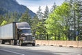 Brown long hauler big rig semi truck tractor transporting cargo in dry van semi trailer driving on the one way highway road