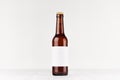 Brown longneck beer bottle 330ml with blank white label on white wooden board, mock up.