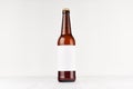 Brown longneck beer bottle 500ml with blank white label on white wooden board, mock up. Royalty Free Stock Photo