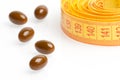 Brown medical pills for dieting in front of measuring tape Royalty Free Stock Photo
