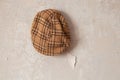 Brown mens cap in a cage hanging on the white wall