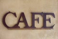 Brown Metal Cafe Sign against a Textured Wall