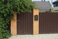 Brown metal door and part of the wall of the fence