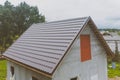Brown metal tile on the roof of the house. Corrugated metal roof and metal roofing. Modern roof made of met Royalty Free Stock Photo