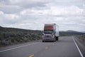 Brown modern semi truck with trailer driving long Nevada highway