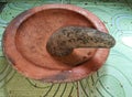 A brown mortar made of clay and a mortar made of natural stone on top of patterned green ceramic