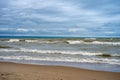 Brown muddy sea waves and dramatic clouds on a beach Royalty Free Stock Photo