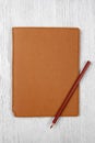 Brown notebook and a pencil on white wooden table, top view Royalty Free Stock Photo