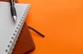Brown notebook, white spring notebook and black pen on bright orange background with copy space Royalty Free Stock Photo