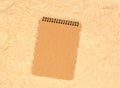 Brown notepad with a craftpaper on a background of beige crumpled parchment paper. Loose-leaf notebook