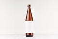 Brown NRW beer bottle 500ml with blank white label on white wooden board, mock up.