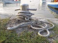 Brown old anchor rope wrapped around dock pier post. Anchor rope in the port, ship mooring tool. Close-up of textile rope on a Royalty Free Stock Photo