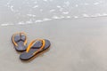 Brown and orange beach slippers on sandy ocean beach, summer vac Royalty Free Stock Photo
