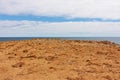 Brown and orange desert landscape in front of clear blue sea