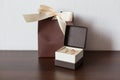 Brown pack and delicate little brown box with wedding rings on a wooden surface