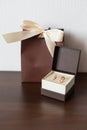 Brown pack and delicate little brown box with wedding rings on a wooden surface Royalty Free Stock Photo