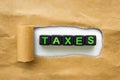 Brown package kraft paper torn to reveal black cubes with the word TAXES. Concept tax season Royalty Free Stock Photo