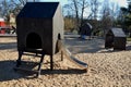 Brown painted wooden house on a playground with a sandpit. stainless steel slides shine in the sandy beach. wooden benches separat Royalty Free Stock Photo