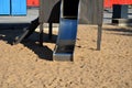 Brown painted wooden house on a playground with a sandpit. stainless steel slides shine in the sandy beach. wooden benches separat Royalty Free Stock Photo