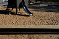 Brown painted wooden house on a playground with a sandpit. stainless steel slides shine in the sandy beach. wooden benches separat Royalty Free Stock Photo