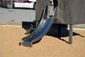 Brown painted wooden house on a playground with a sandpit. stainless steel slides shine in the sandy beach. wooden benches separat Royalty Free Stock Photo