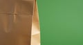 Brown paper bag with a folded top against a solid green background. The bag\'s texture Royalty Free Stock Photo