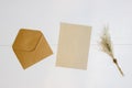 Brown paper with brown envelope with flowers over the white wooden background.